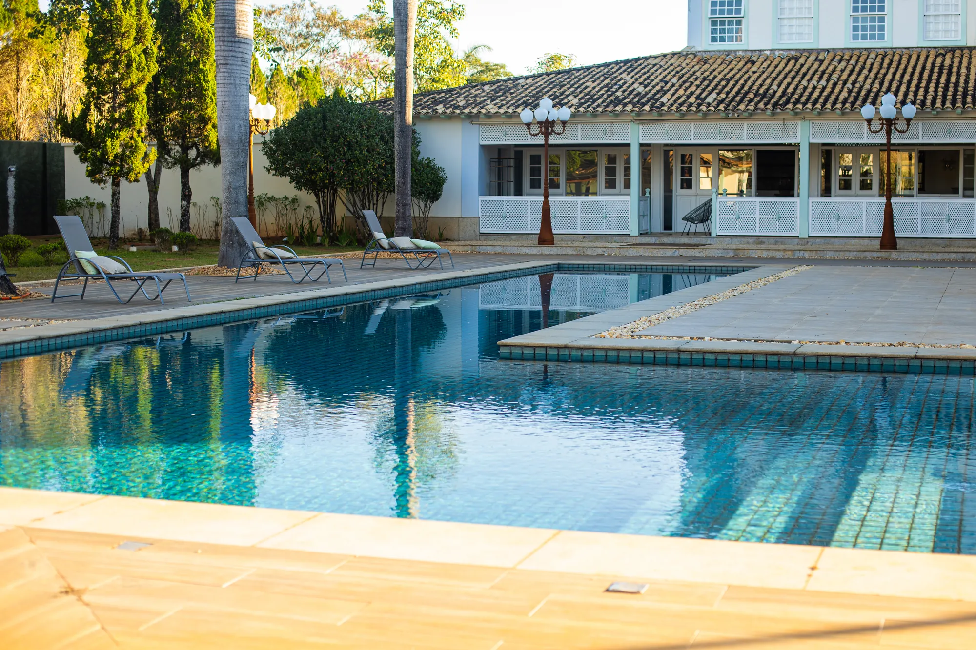 Piscina da pousada com espreguiçadeiras e a casa colonial ao fundo